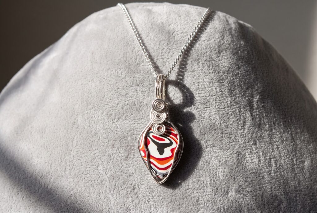 Genuine Fordite teardrop pendant with layered automotive paint patterns, wrapped in silver-plated wire and supplied with a 20-inch chain.FORDITE DETROIT AGATE